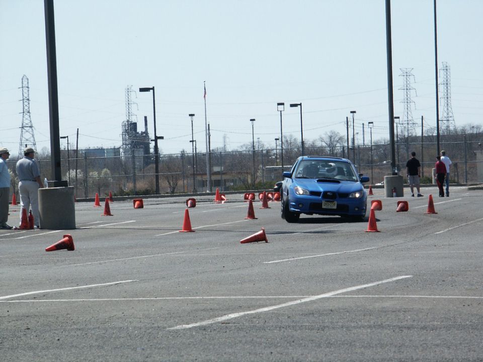 Blue Subaru WRX STI with license plate JPN-759 navigating an autocross course marked by orange cones