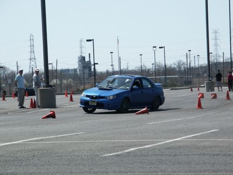 2001 Mercury Grand Marquis - A blue Subaru Impreza WRX sedan is driven through an autocross course with orange cones marking the path.