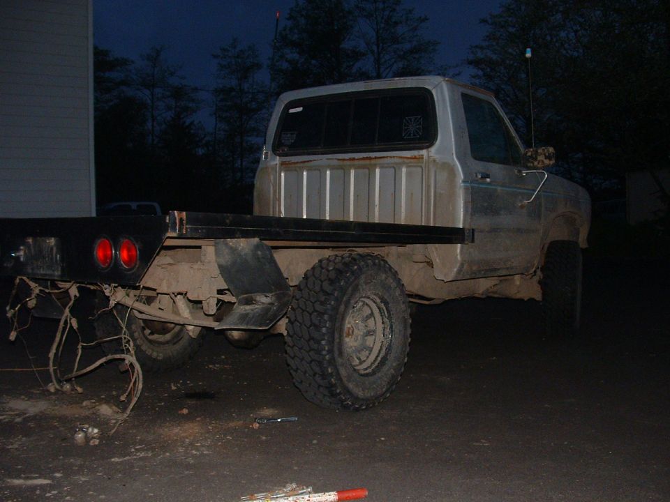 Silver flatbed truck, rear view, with exposed wiring and dual taillights
