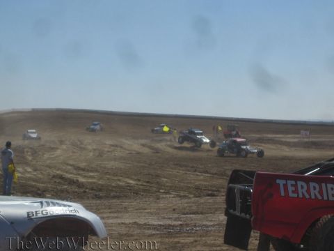 1990 Ford Bronco - Off-road trucks and buggies race across a dusty dirt course while a red Terrible Herbst truck sits in the foreground.