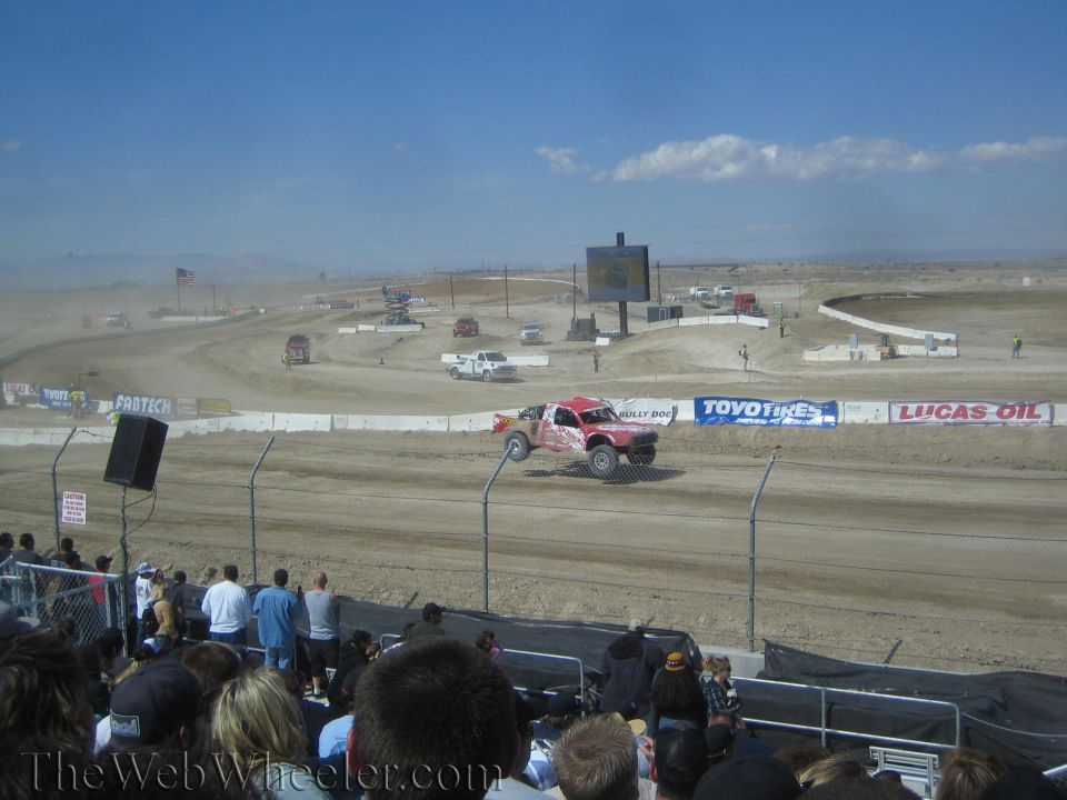 Off-road race truck on a dirt short-course track with desert backdrop