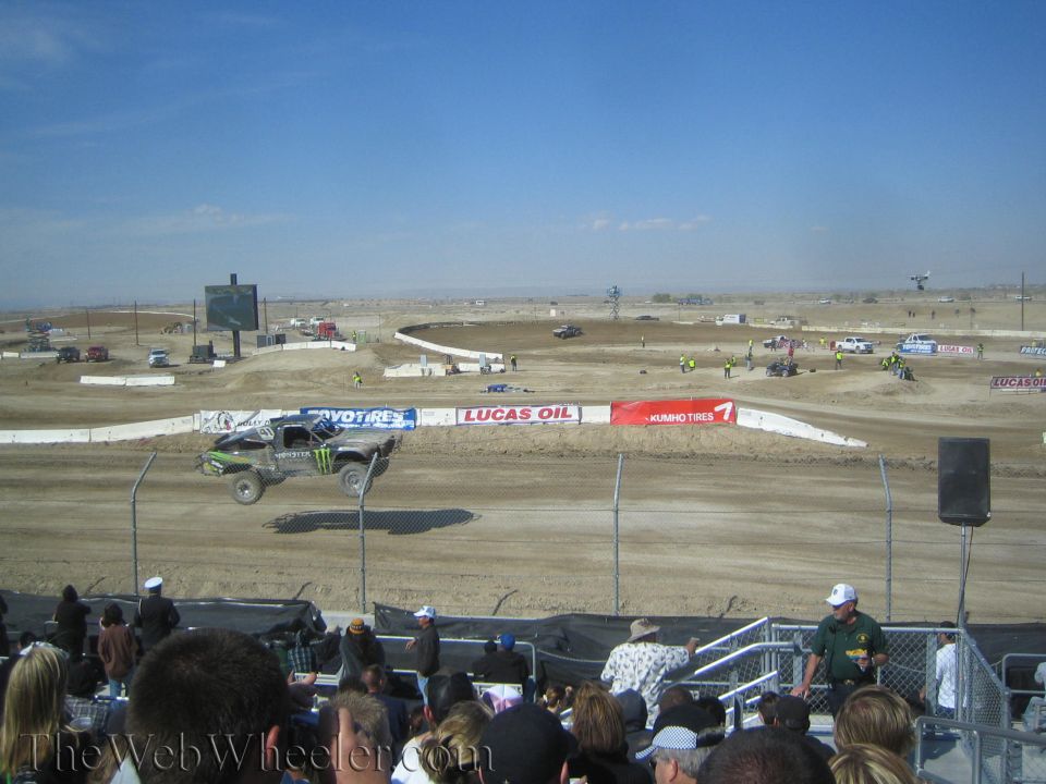 Off-road truck jumping in front of a grandstand crowd at a dirt track
