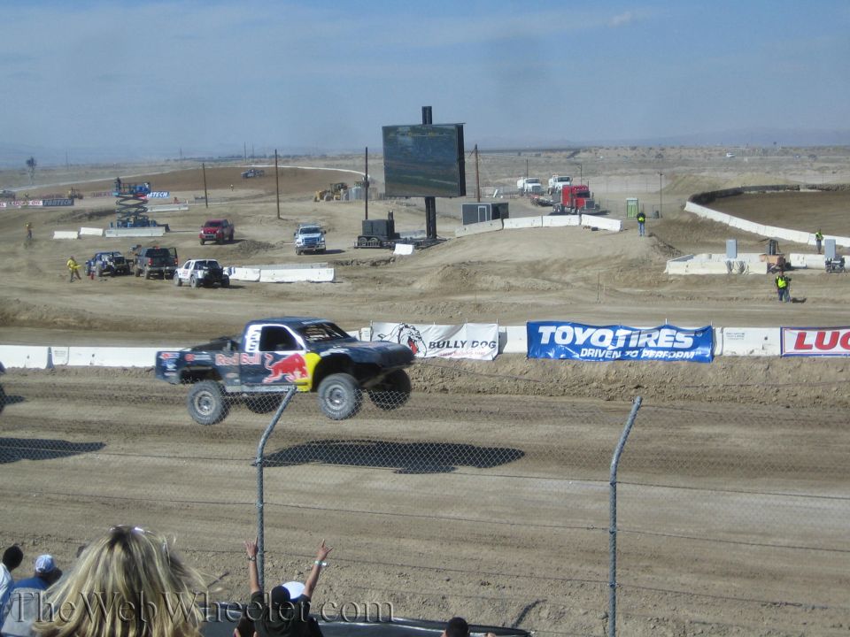 Red Bull off-road truck jumping past Toyo Tires banner at dirt track