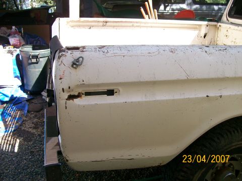 1978 Ford F-250 - A white pickup truck bed shows signs of wear and tear, with rust visible on the fender and tailgate area.