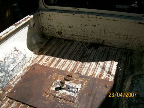 1978 Ford F-250 - The interior of a white truck bed shows a ribbed floor and a rusty metal plate with a central bolt.