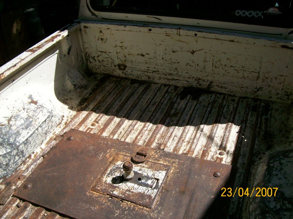 White truck bed interior with ribbed floor and rusty metal plate