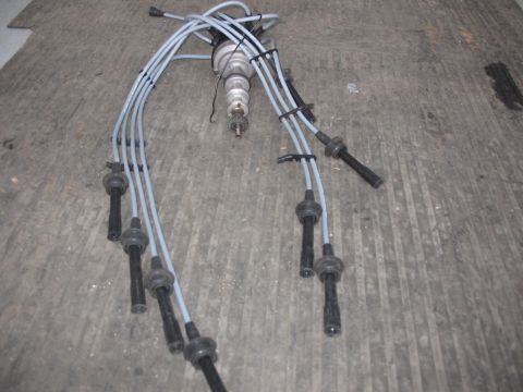 1964 Ford 427 - A distributor and spark plug wires are laid out on a textured surface, with a website logo visible in the lower right corner.