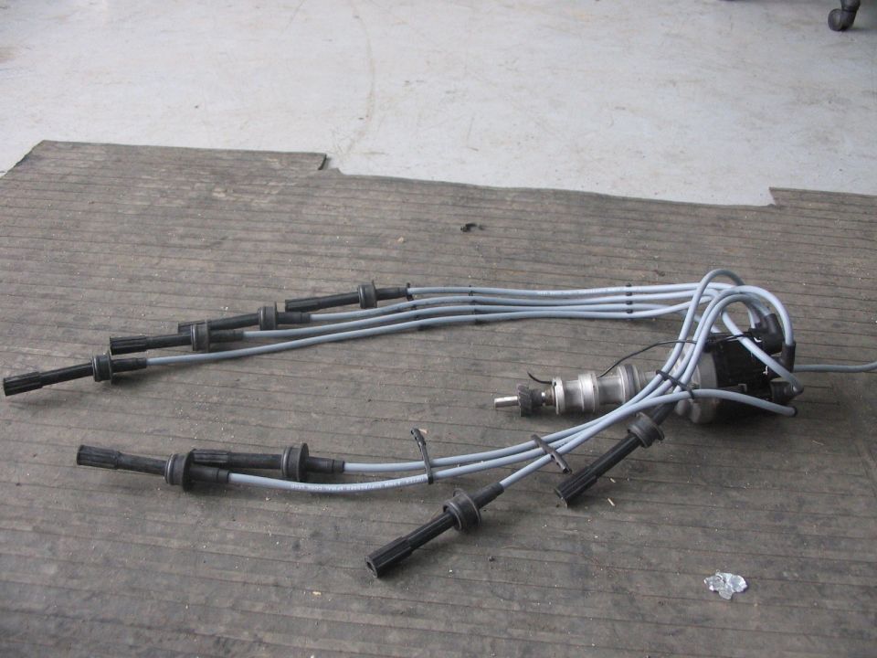 Spark plug wires and a distributor assembly laid out on a wooden surface