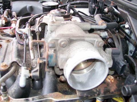 1999 Ford Crown Victoria - Close-up view of an engine throttle body, with a SuperMotors logo visible at the bottom right.