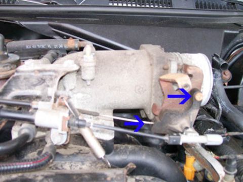 1999 Ford Crown Victoria - Close-up view of a throttle body assembly with visible cables and hoses.