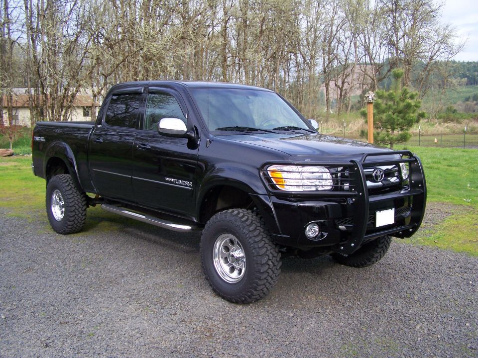 Lifted black Toyota Tundra Double Cab with brush guard and off-road tires, 3/4 front view