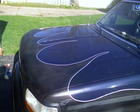1993 Ford Bronco - A dark blue truck with custom flame pinstriping on the hood is parked outside on a sunny day.
