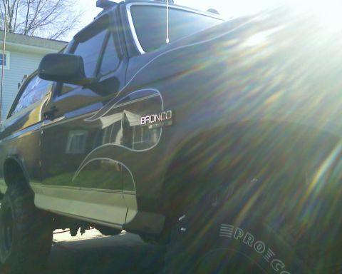 1993 Ford Bronco - A dark green Ford Bronco with distinctive pinstriping is viewed from a low front quarter angle.