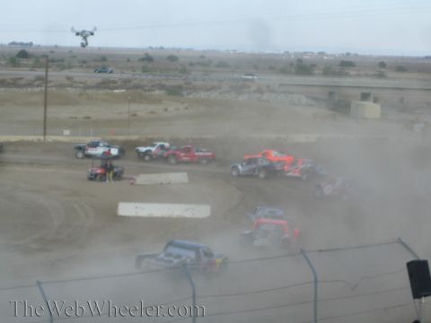 1990 Ford Bronco - Off-road race trucks navigate a dusty dirt course as a camera drone hovers overhead.