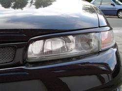 1995 Ford Probe - Detail of a car's headlight assembly and grille, with another vehicle in the background.