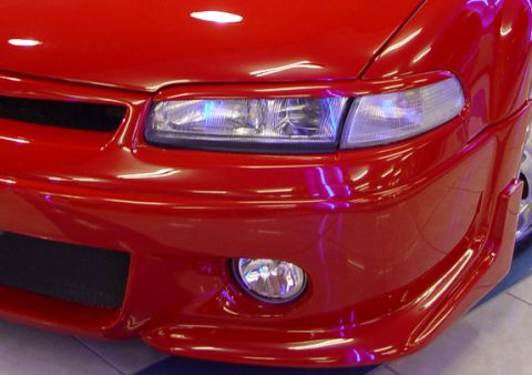 1995 Ford Probe - The front of a red car is shown, with a focus on the headlight and fog light assembly.