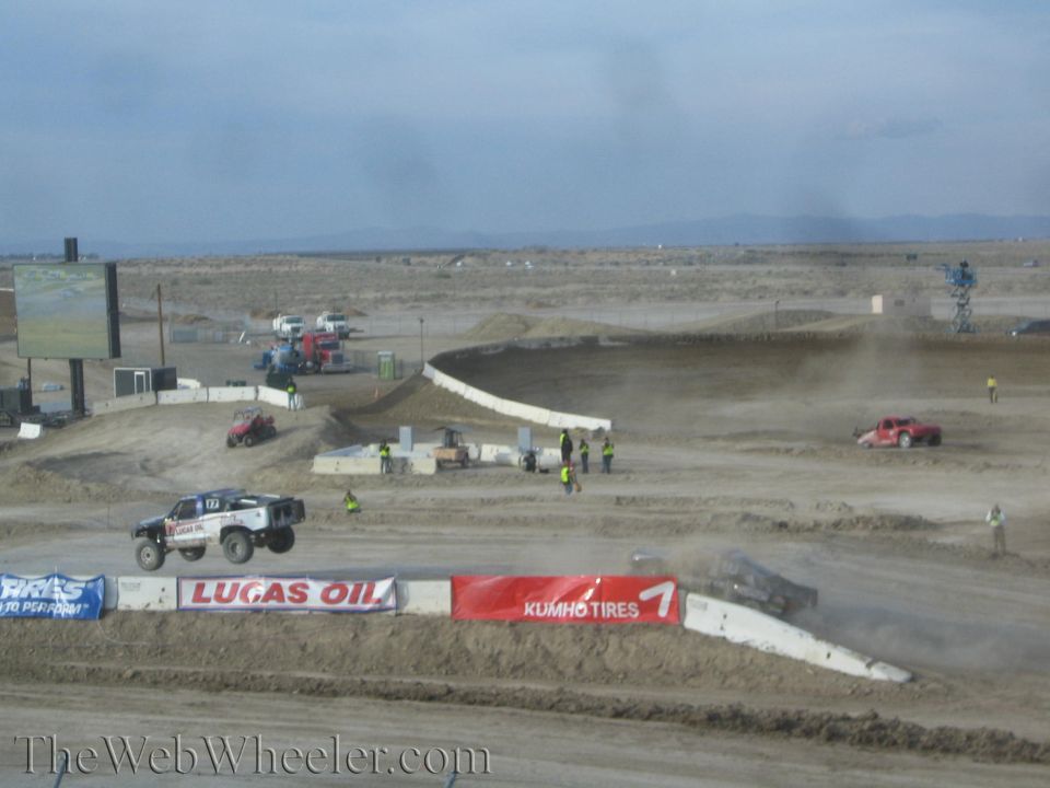 Off-road race truck jumping on a wide desert short-course track