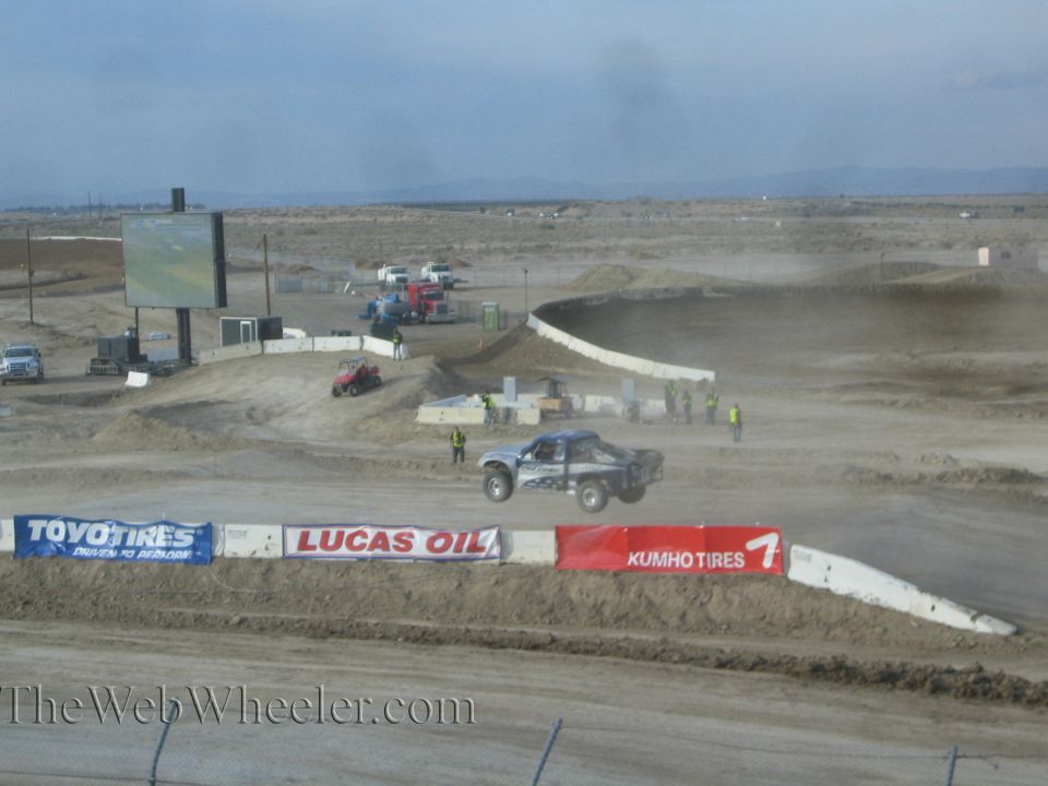 Blue off-road race truck on a wide desert dirt track