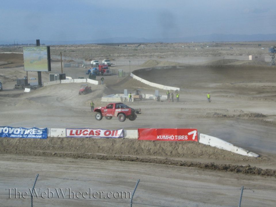 Red off-road race truck jumping on a desert short-course track
