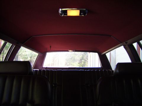 1982 Ford LTD Crown Victoria - Interior shot taken from the front seats looking rearward, showing a clean burgundy cloth headliner with an illuminated dome light and the…