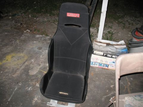 1985 Ford Crown Victoria LTD - A black Kirkey racing seat is shown outdoors next to a bag of tile wet.
