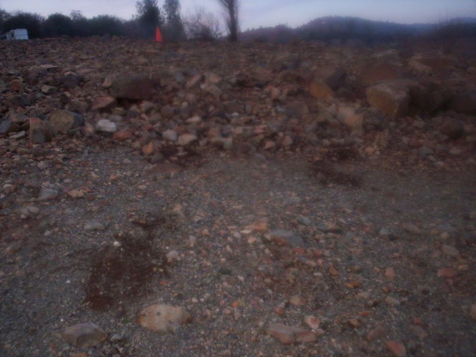 White trailer parked on a rocky, uneven terrain with an orange cone in the background