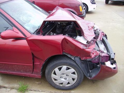 1996 Ford F-350 - A red car sustained heavy front-end damage, with its hood crumpled and windshield shattered.