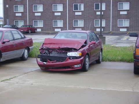 1996 Ford F-350 - This red sedan has significant front-end damage, including a crumpled hood and bumper.