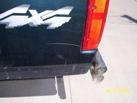 1996 Ford F-350 - A close-up of a truck's rear quarter panel shows a 4x4 decal and dual exhaust pipes.