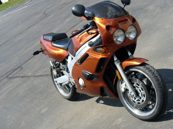 Orange sportbike motorcycle parked on asphalt. Front wheel and fairing visible