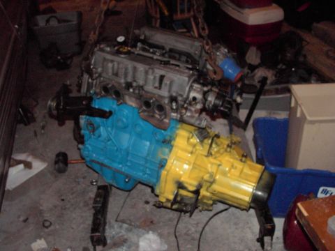 1989 Ford Probe - Engine and transmission assembly, painted blue and yellow, being worked on.