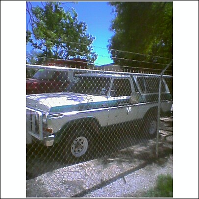 1979 Ford Bronco - A two-tone 1978 Ford Bronco is parked behind a fence, with another vehicle visible behind it.