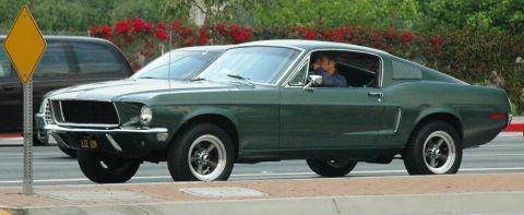 1991 Ford Taurus - A 1967 Ford Mustang Fastback is seen driving on a street next to another vehicle.