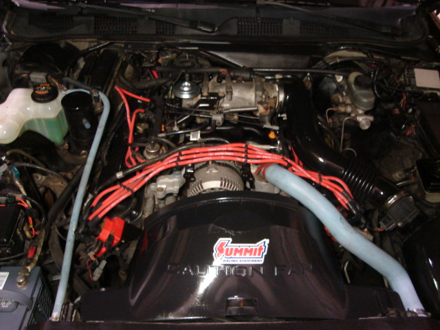 1992 Ford Crown Victoria engine bay with red spark plug wires and a black Summit Racing air intake cover