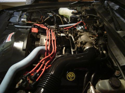 1992 Ford Crown Victoria - The engine bay of a car, red spark plug wires and an 'ENGINE OIL' sticker.