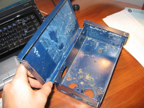 1974 Ford F-100 - Hand holds open a blue metal electrical box, revealing its interior and a caution label.