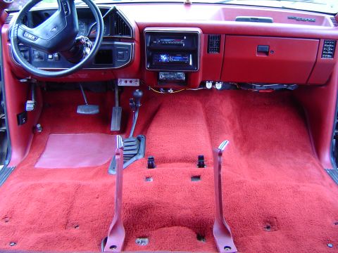 1989 Ford Bronco - The interior of a 1987 Ford F-Series truck shows a red carpet and manual transmission shifter.