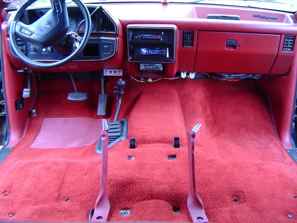 Red Ford truck interior with seats removed, new red carpet, and stacked aftermarket stereo units