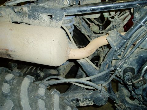 2000 Ford E350 - Close-up view of the exhaust pipe and suspension components of a vehicle.