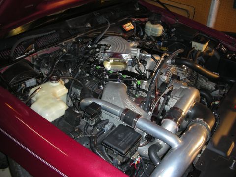 1992 Ford Crown Victoria - Custom engine bay features a polished supercharger and intake system, with a glimpse of the red exterior.