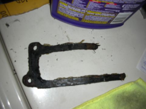 1992 Ford Crown Victoria - A heavily rusted metal bracket is shown, likely a replacement part for a vehicle.
