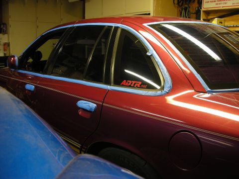 1992 Ford Crown Victoria - A red 1992 Ford Crown Victoria is prepped for detailing with blue tape applied to its exterior.
