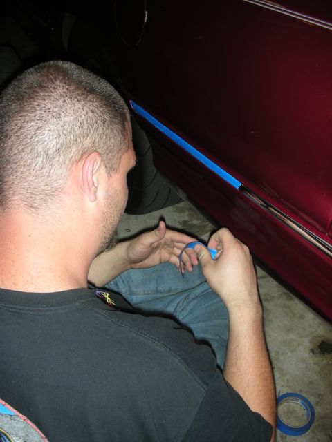 1992 Ford Crown Victoria - Man applies masking tape to car door trim during a repair or modification.