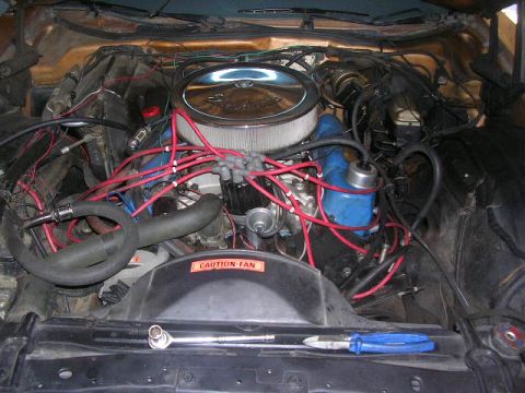1975 Ford Ranchero - A close-up view of a V8 engine bay, with a prominent air filter and numerous red spark plug wires.