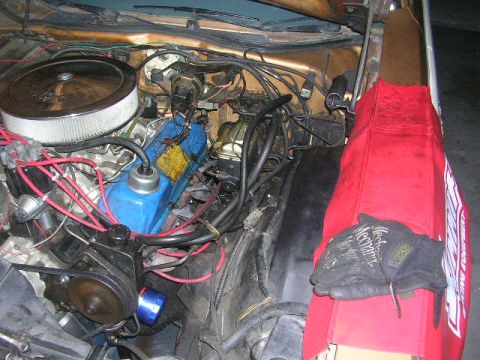 1975 Ford Ranchero - Close-up view of a vehicle's engine bay, showing various components and a red fender cover.