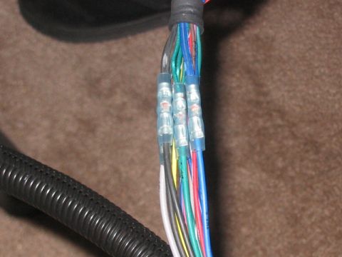 1991 Ford Bronco - A close-up view of a vehicle's wiring harness, showing several crimped connectors and a bundle of colored wires.