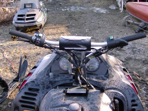 1982 Chevrolet C/K Pickup - Interior view of a snowmobile's handlebars and gauges, with another snowmobile parked behind it.