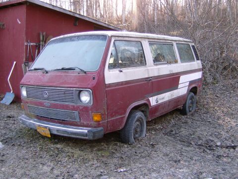 1982 Chevrolet C/K Pickup - This maroon and white van sits in a wooded area with a red shed nearby.