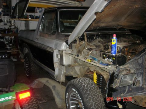 1979 Ford Bronco - Ford Bronco in a garage, undergoing maintenance with the hood and fender removed.