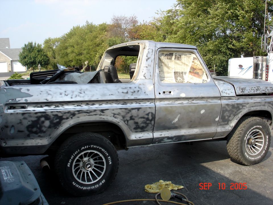 Side view of a 1979 Ford Bronco in primer, undergoing restoration